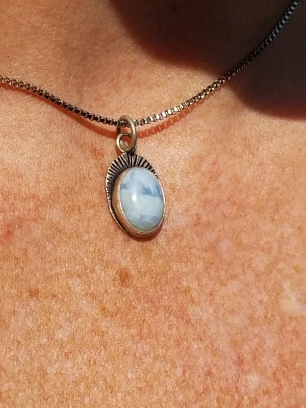 Woman wearing small light blue necklace